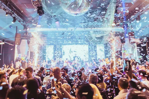 Guests celebrating under a mirror ball as confetti falls.