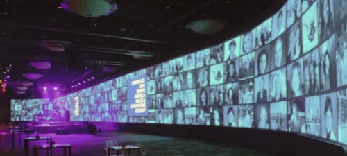 A wide conference stage flanked by large presentation screens.