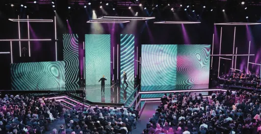 A televised stage set with LED walls and a live audience.