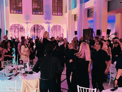 Guests dancing at an evening reception in a light-filled venue.